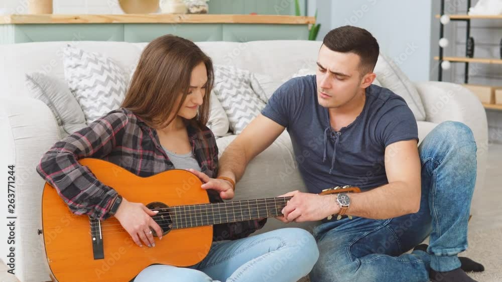 Young girl learning guitar from male teacher at home. Showing guitar chords Young girl learning guitar from male teacher at home. Showing guitar chords