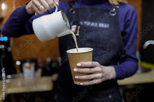 Young barista girl pouring a cappuccino glass.