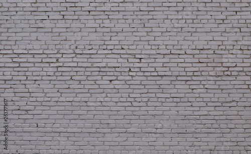 Ordered texture of a nervous brick wall of an old building painted with white paint