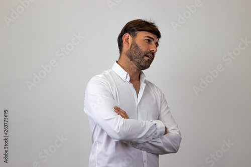 Fashion portrait of handsome young man with brown hair making an interesting face facing forwards and looking at the side. Isolated on white background.