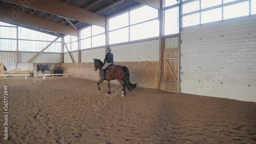 Woman riding a horse in riding stable photo