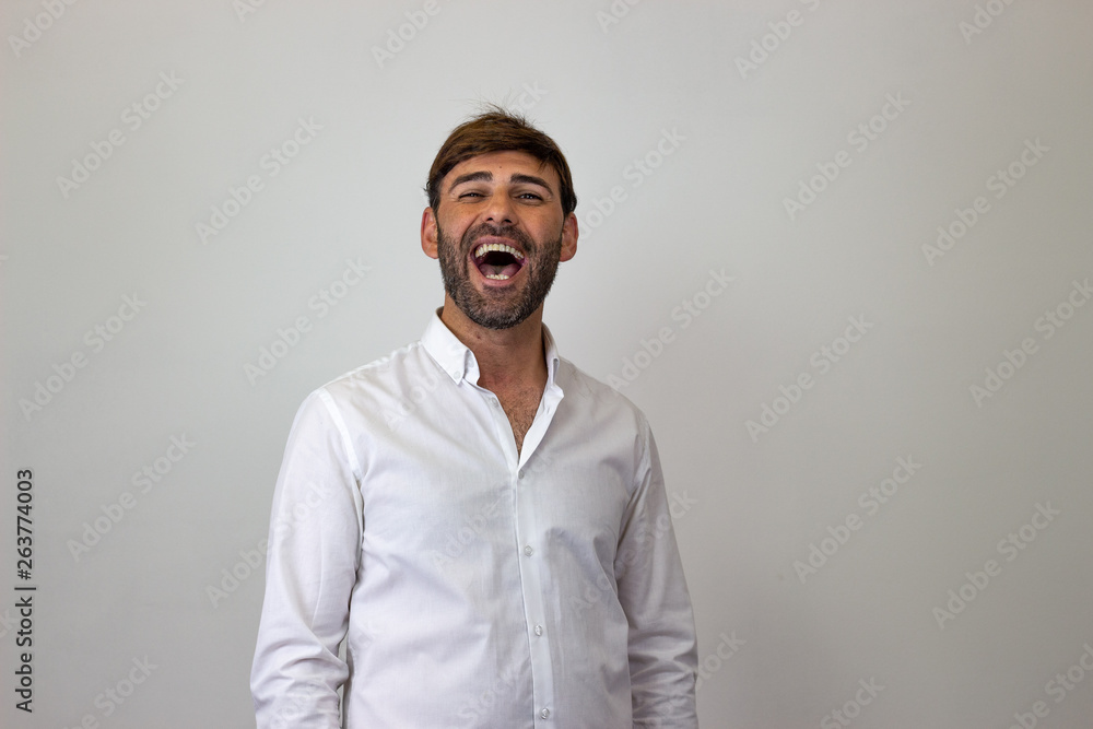 Obraz premium Fashion portrait of handsome young man with brown hair laughing, their back facing the camera and looking at the camera. Isolated on white background.
