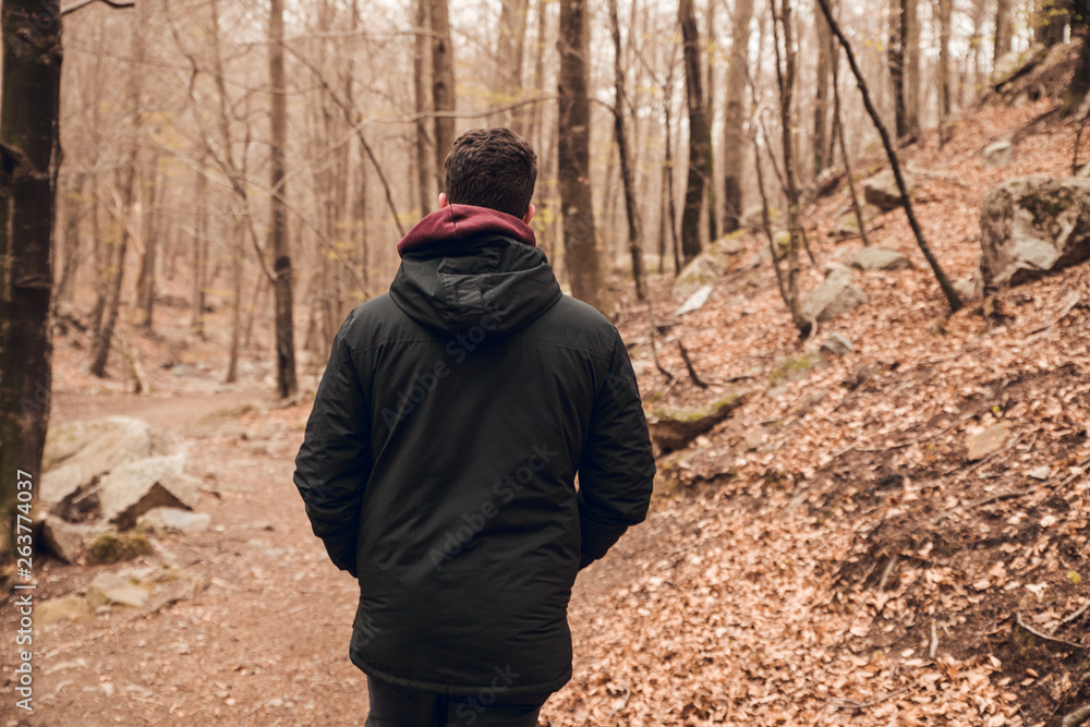 Boy walking with black coat in autumn forest Boy walking with black coat in autumn forest