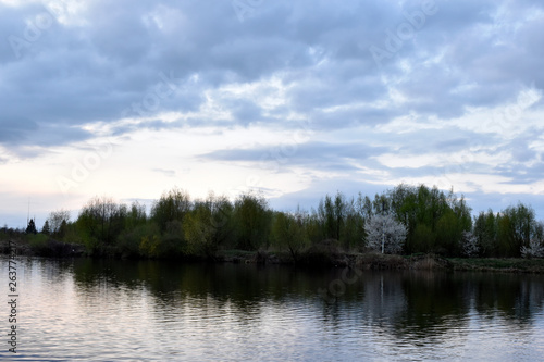 The opposite bank of the river Mukhavets and the beautiful sky during sunset