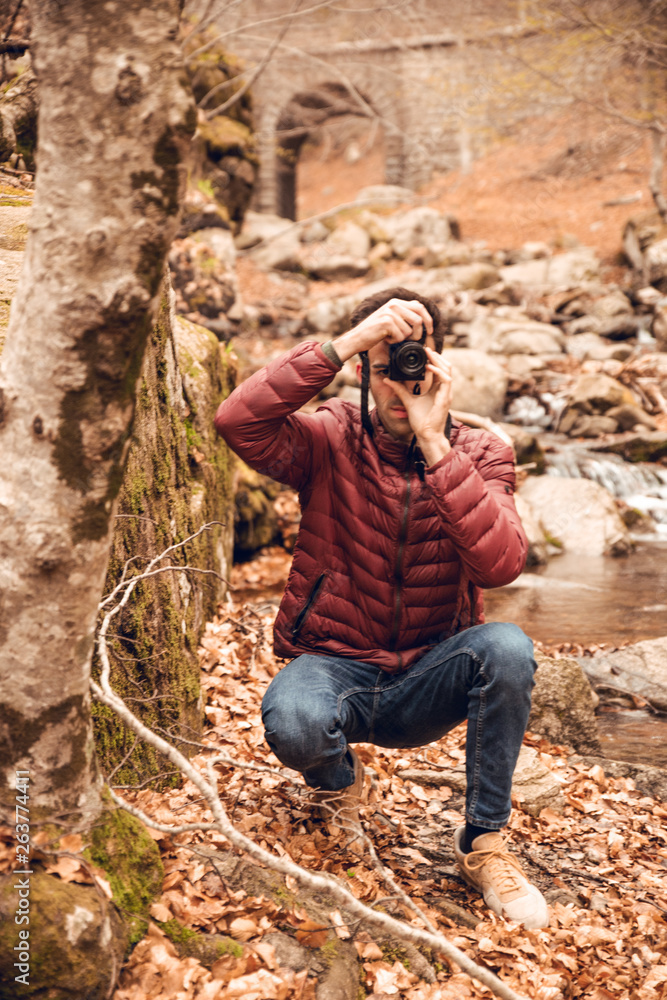 Boy with red coat taking pictures in forest in autumn Boy with red coat taking pictures in forest in autumn