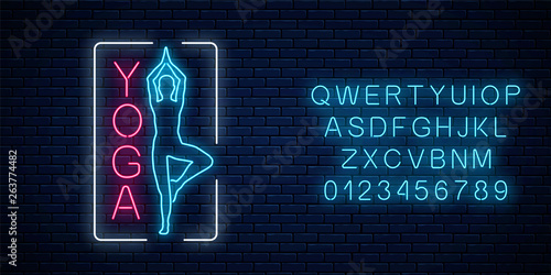 Neon glowing sign of yoga exercices in rectangle frame with alphabet. Street advertising signboard of gymnastics club.