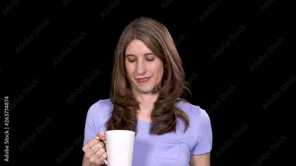 A Caucasian woman tastes her coffee and then adds alcohol while standing on a black studio background A Caucasian woman tastes her coffee and then adds alcohol while standing on a black studio background