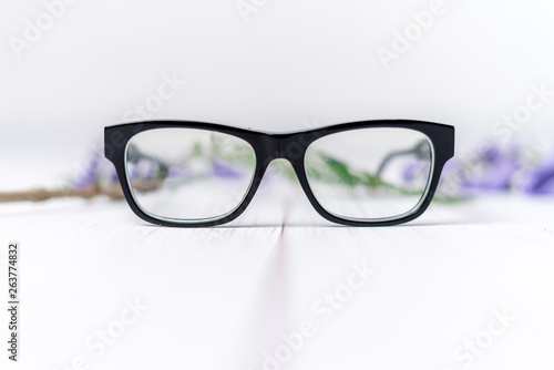 lentes de pasta negros sobre fondo blanco y flores purpuras