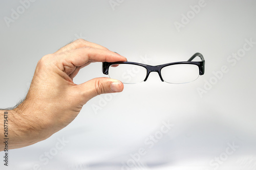 A male hand holding a half frame eyeglasses isolated over white.