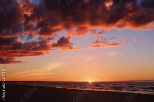 Setting sun  calm sea and colourful clouds at the seaside on a dusk time