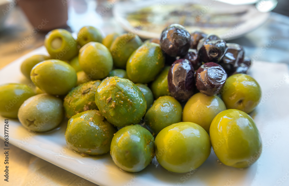 Spiced olives in a small plate on the tapas bar table a typical Spanish black and green split olive. Spiced olives in a small plate on the tapas bar table a typical Spanish black and green split olive.