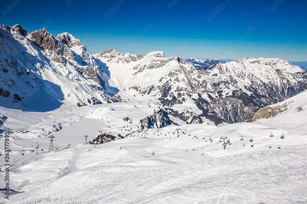 Beautiful winter landscape with Swiss Alps. Skiers skiing in famous Engelgerg - Titlis ski resort, Switzerland, Europe