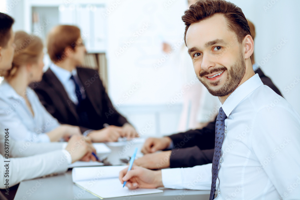 Businessman headshot against a group of business people at a meeting or negotiation in office Businessman headshot against a group of business people at a meeting or negotiation in office