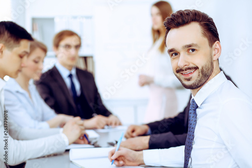 Businessman headshot against a group of business people at a meeting or negotiation in office