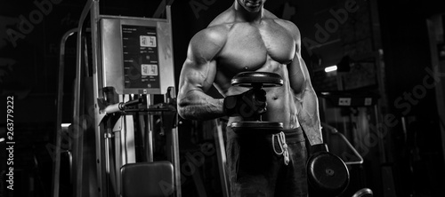 Strong fitness man doing arm workout with barbells in the gym