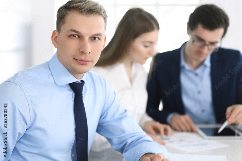 Group of business people discussing questions at meeting in modern office. Headshot of businessman at negotiation. Teamwork, partnership and business concept Group of business people discussing questions at meeting in modern office. Headshot of businessman at negotiation. Teamwork, partnership and business concept