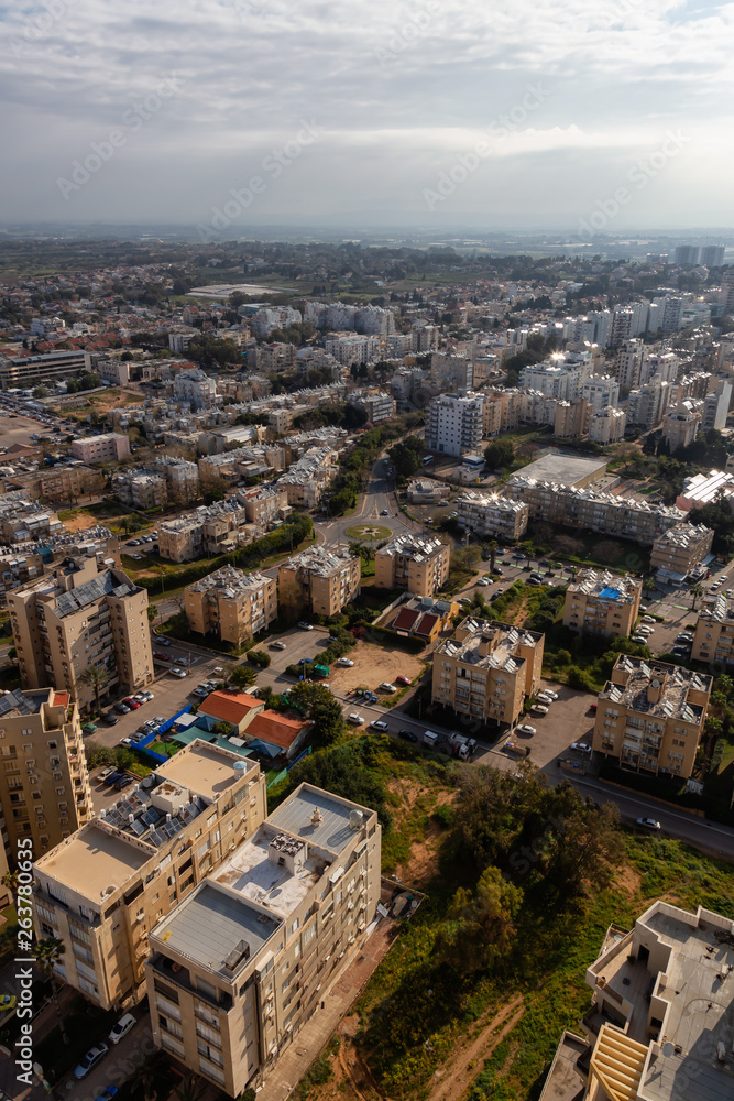 Aerial view of a residential neighborhood in a city during a cloudy and sunny sunrise. Taken in Netanya, Center District, Israel.