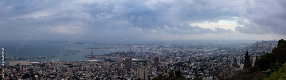 Beautiful panoramic view of a city on the coast of Mediterranean Sea during a cloudy sunset. Taken in Haifa, Israel.