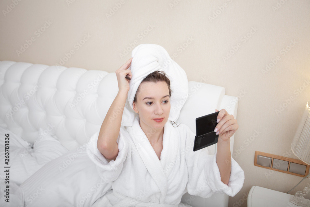 Young pretty european woman in bathrobe takes care of her skin and body after shower. Make up brush. Getting ready for work doing morning makeup. Skin moisturizing. Close up. Young pretty european woman in bathrobe takes care of her skin and body after shower. Make up brush. Getting ready for work doing morning makeup. Skin moisturizing. Close up.