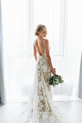 Awesome bride in a long wedding dress with a beautiful bouquet in hand and with charming smile