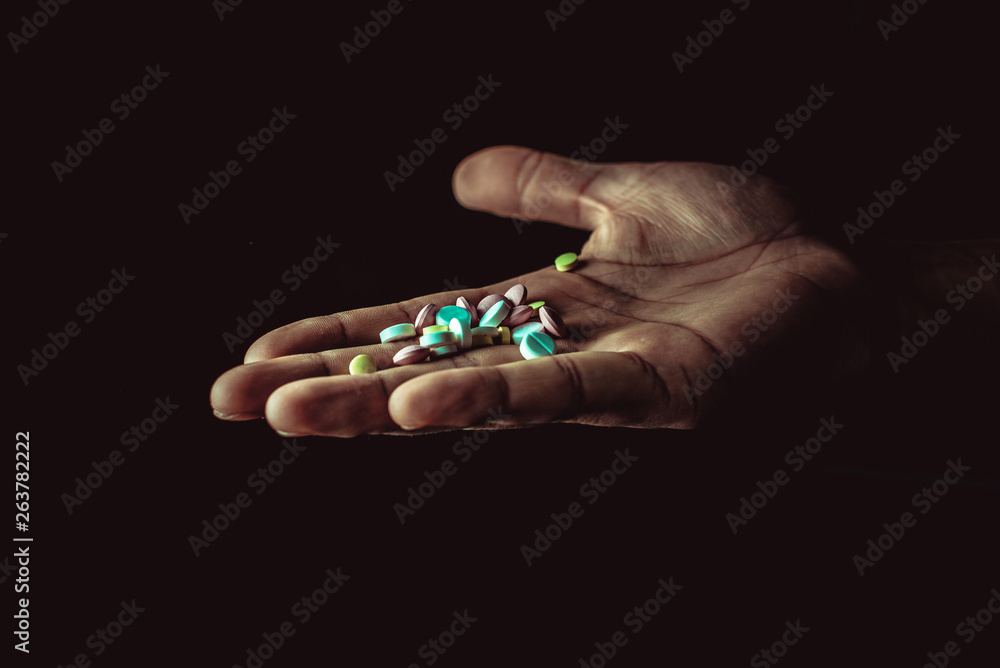 pills in hand on black background
