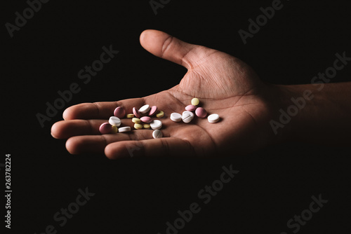 pills in hand on black background