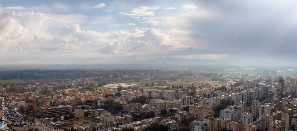 Aerial panoramic view of a residential neighborhood in a city during a cloudy sunrise. Taken in Netanya, Center District, Israel.