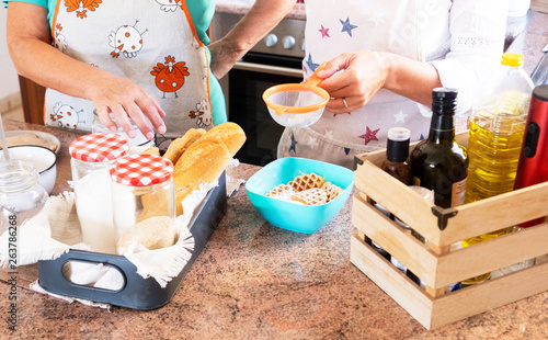 Two caucasian women in the kitchen with aprons and discussing about the meal to prepare photo