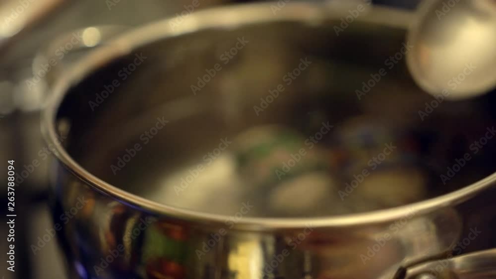 Putting chicken eggs folded into decorative foil into boiling water. Pot full of boiling water. Cooking easter eggs with pattern decoration. Putting chicken eggs folded into decorative foil into boiling water. Pot full of boiling water. Cooking easter eggs with pattern decoration.