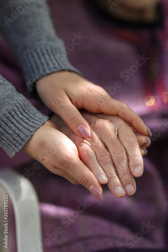 Young caregiver holding seniors hand. Elderly concept