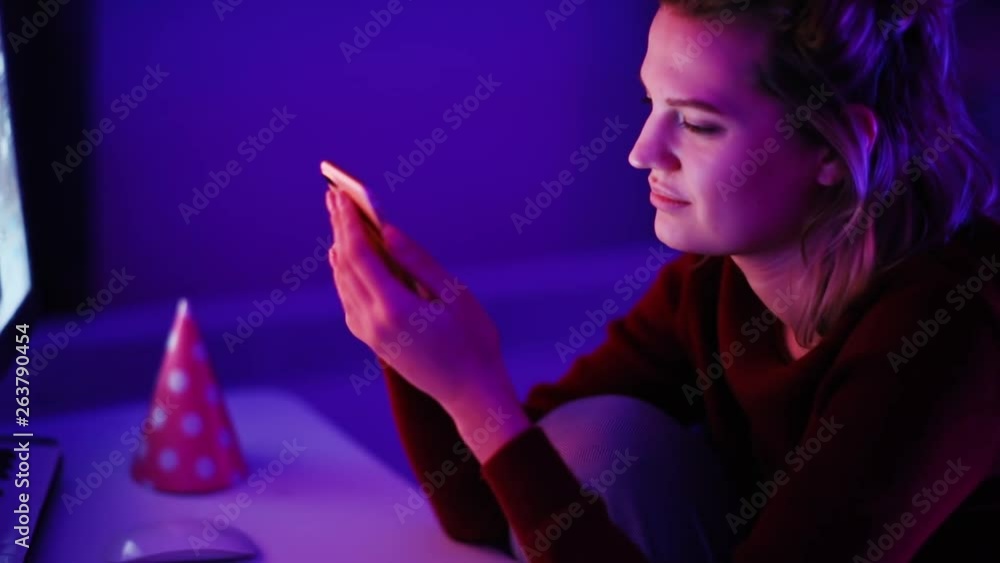 Close-up of smiling young woman browsing news on a smartphone relaxing in the comfort room at home. Close-up of smiling young woman browsing news on a smartphone relaxing in the comfort room at home.