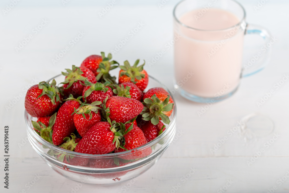 Fresh strawberry in a bowl and glass of milk on wooden background. Fresh strawberry in a bowl and glass of milk on wooden background.