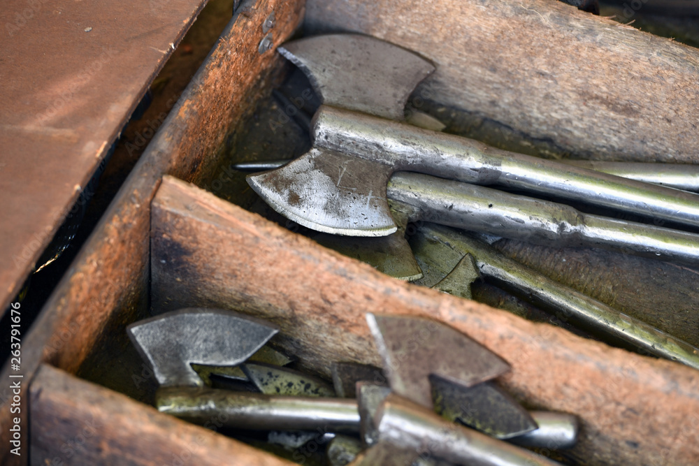 Shiny handmade middle ages axes in a wooden box on a traditional market. Shiny handmade middle ages axes in a wooden box on a traditional market.