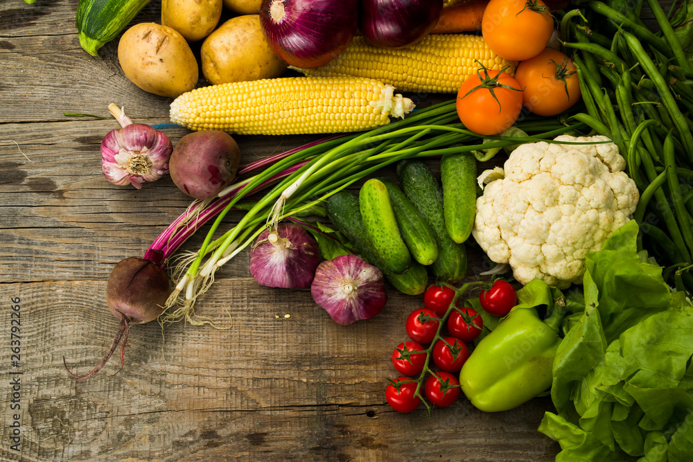 fresh crop of different vegetables on a wooden table, top view with free space for text, top view