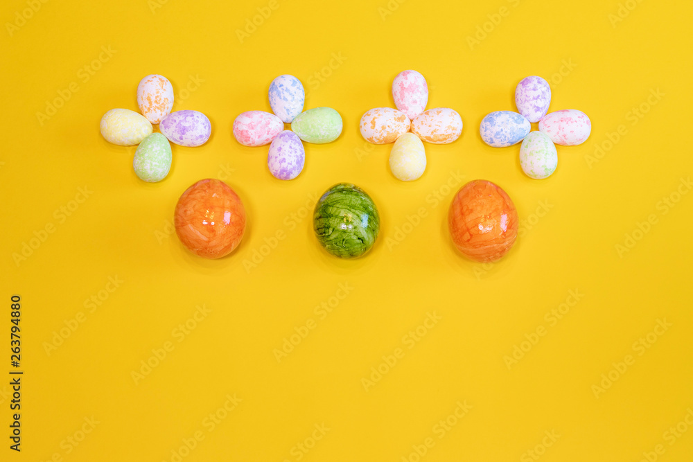 A lot of colorful Easter eggs on a yellow background. Top view, minimal Easter concept. Happy Easter card  with free, empty space.