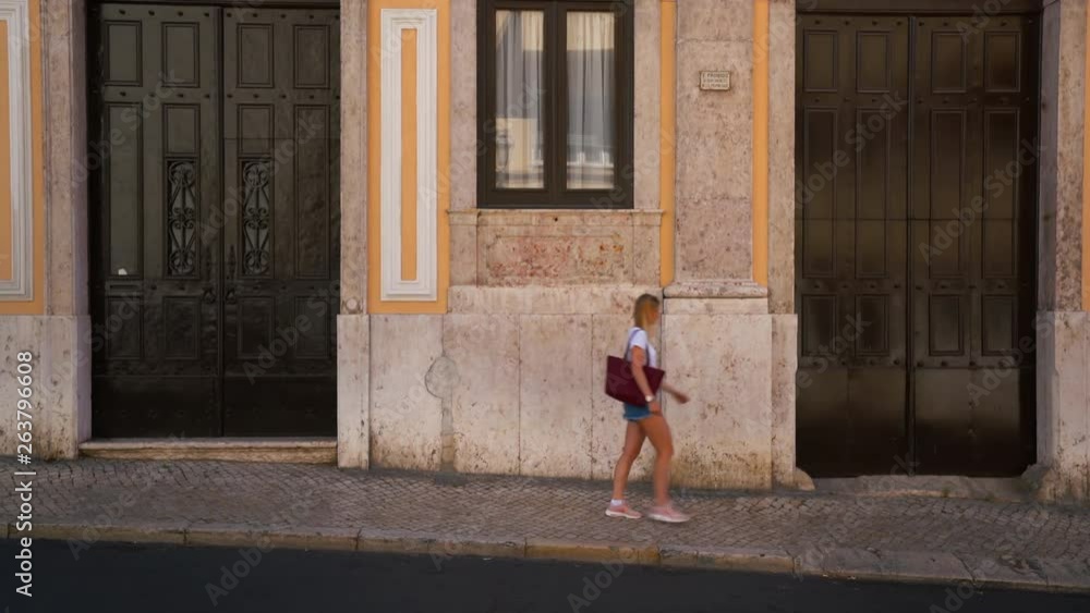 A Girl is walking through the frame in front of an iconic Wall in Lisbon, Portugal. A Girl is walking through the frame in front of an iconic Wall in Lisbon, Portugal.