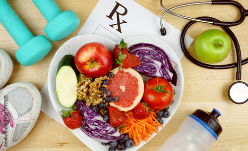 Prescription for good health overhead with stethoscope, healthy fresh food and exercise equipment.
