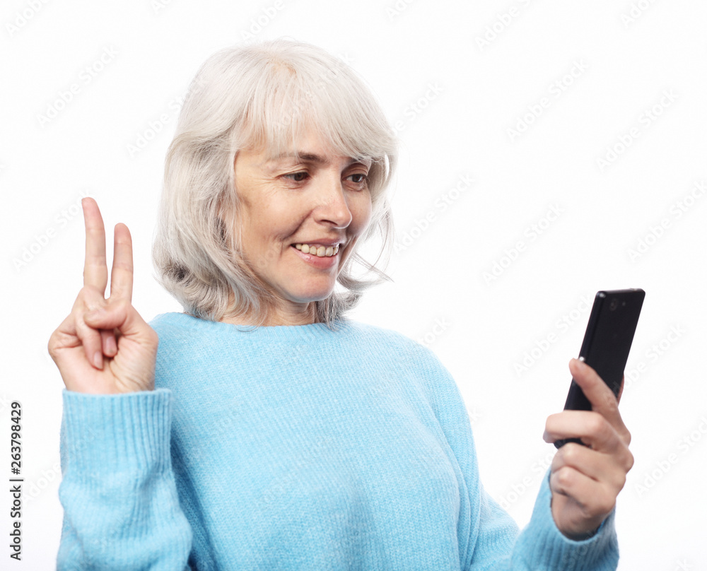 Smiley senior woman is holding a new smartphone in her hand. Smiley senior woman is holding a new smartphone in her hand.