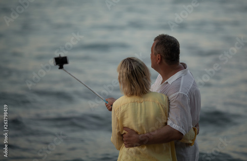 A middle-aged couple makes a selfie photo beside the sea