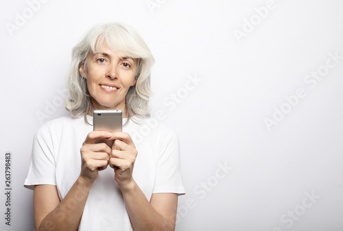 ifestyle, family and people concept: old grandmother is talking to her grandchildren by phone, smiling and greeting them