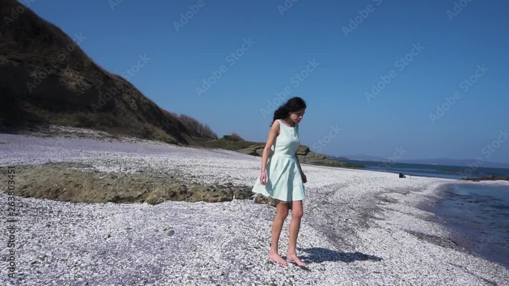 Slow motion shot of pretty girl in white dress walk on the beach Slow motion shot of pretty girl in white dress walk on the beach