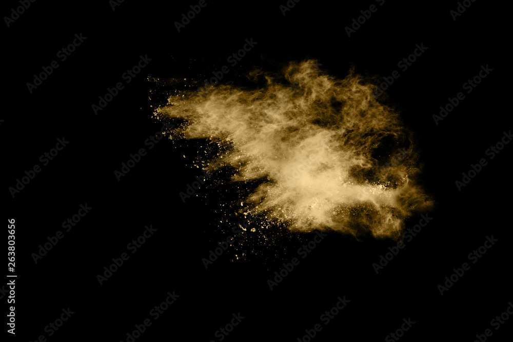 Golden powder explosion on black background. Freeze motion.