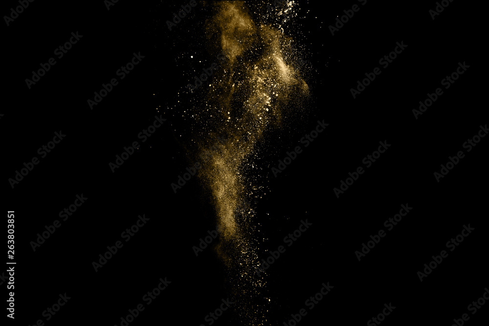 Golden powder explosion on black background. Freeze motion.