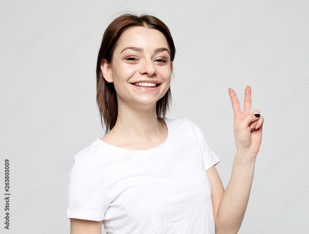 happy girl looking at camera with smile and showing peace sign with fingers happy girl looking at camera with smile and showing peace sign with fingers