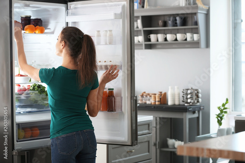 Woman taking food out of fridge at home photo
