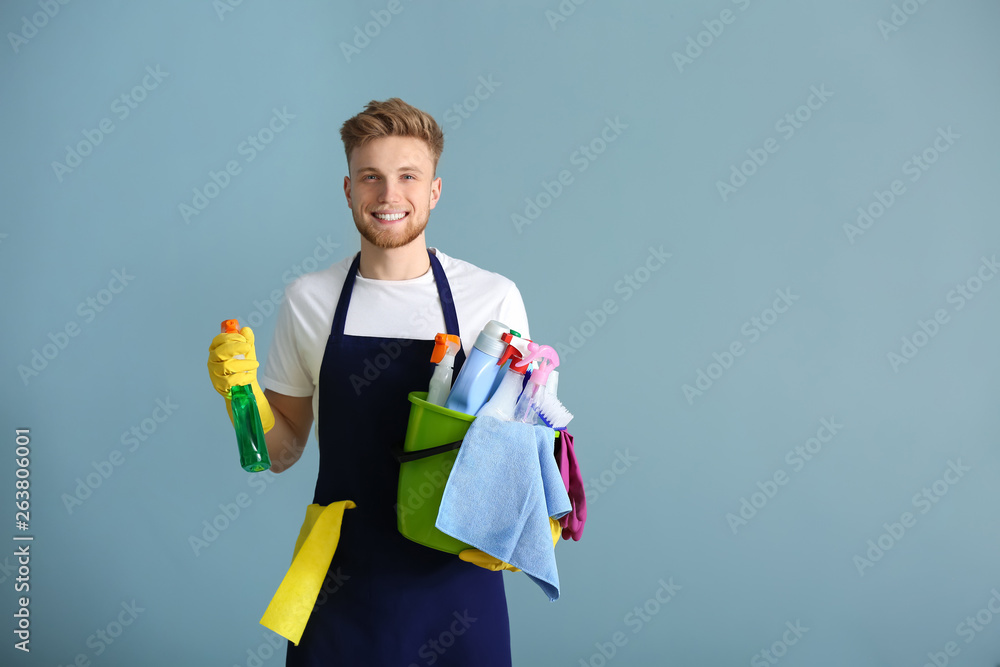 Portrait of male janitor with cleaning supplies on grey background Portrait of male janitor with cleaning supplies on grey background