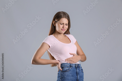 Pregnant woman suffering from toxicosis on grey background