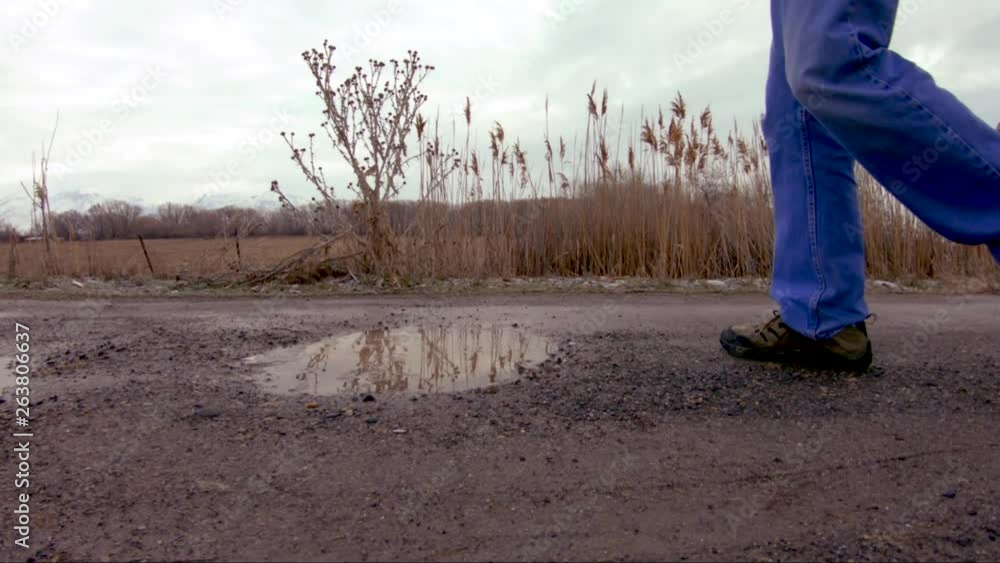 Close up of a puddle that a man steps in while walking by - slow motion