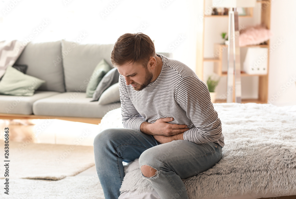 Young man suffering from stomachache at home Young man suffering from stomachache at home