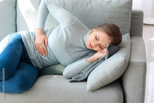 Young woman suffering from stomachache at home
